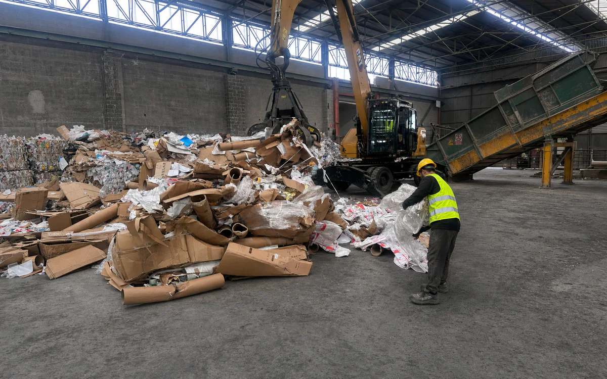 Operatore MPS con casco giallo effettua la cernita di carta e cartone in un’area di lavoro ordinata